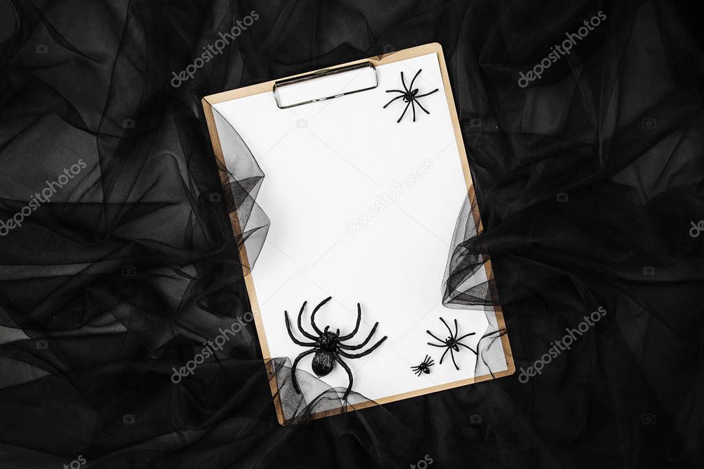 Blank card on clipboard with Spiders and web over black background