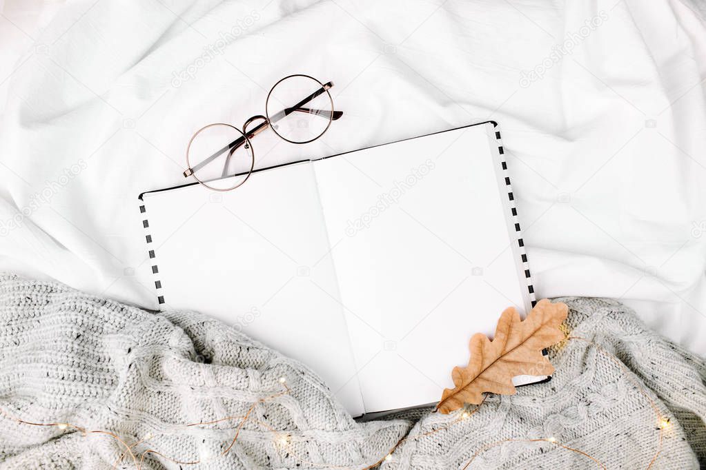 Open Mockup planner and glasses on bed with warm plaid. Copy space. Flat lay, top view