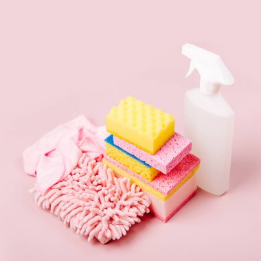 Sprey, sünger, mikrofiber bez ve eldiven üzerinde pembe bir arka plan temizleme