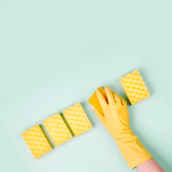 top view of cleaner hand in glove with sponges on blue background