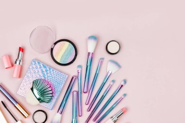 Sanal moda makyaj fırçaları göz farı, toz ve diğer kozmetik ürünleri pastel pembe bir arka plan üzerinde renkli. Düz yatıyordu, en iyi görünümü