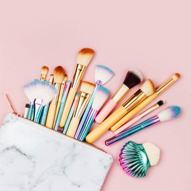 Pastel pembe arka plan üzerinde moda holografik renkli makyaj fırçaları