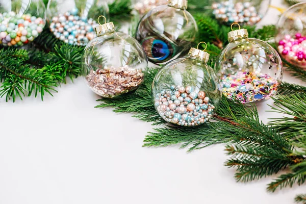 Christmas glass transparent ball with colorful sparkle confetti and fir branch and pine. Holiday concept.