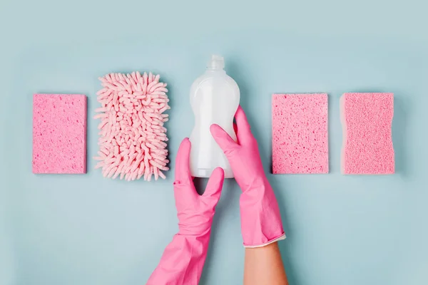 マイクロファイバーの布やスポンジで洗剤のボトルを保持しているピンクのゴム手袋で手 — ストック写真