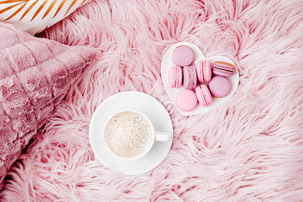 cup of coffee and plate of macaroons on fluffy fur plaid