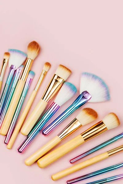 Fashion holographic colored makeup brushes on pastel pink background