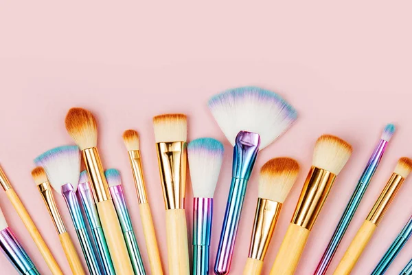 Fashion holographic colored makeup brushes on pastel pink background