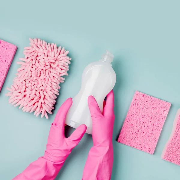 手在粉红色橡胶手套持有一瓶清洁剂与超细纤维布和海绵 — 图库照片