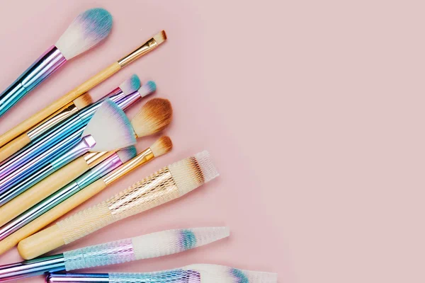 Fashion holographic colored makeup brushes on pastel pink background