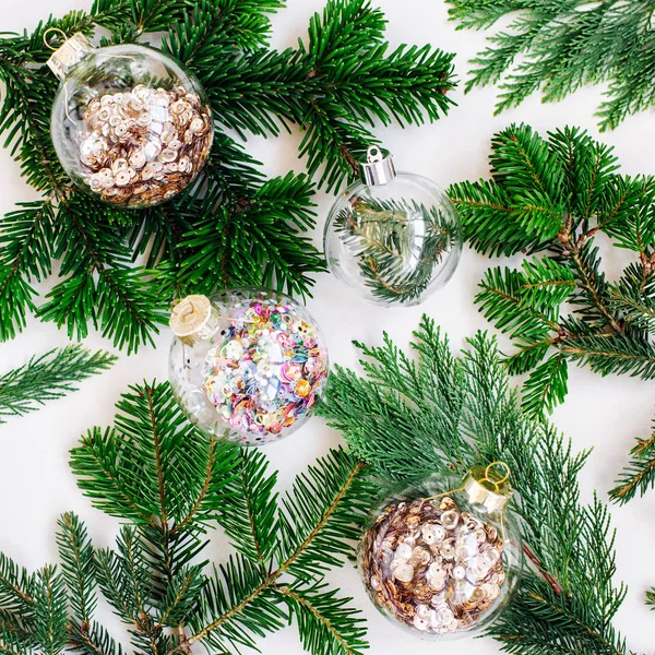 Christmas glass transparent ball with colorful sparkle confetti and fir branch and pine. Holiday concept.