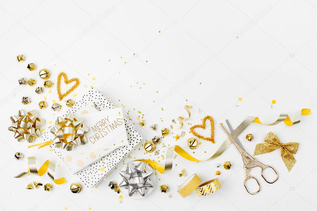 Christmas decorations and gift in gold colors on white background with scissors