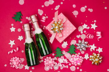 kırmızı zemin üzerine konfeti, yay ve şampanya şişe ile şenlikli arka plan