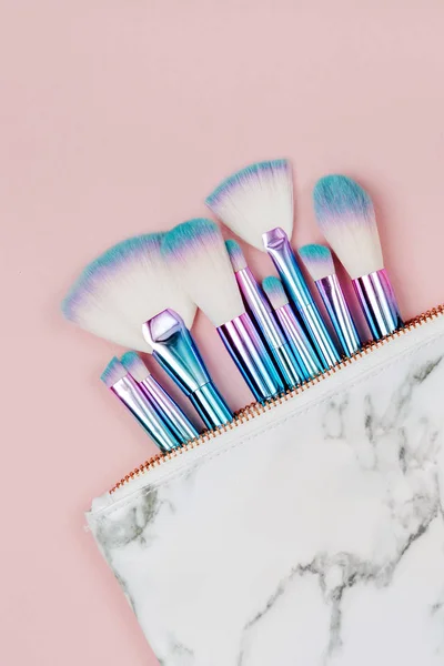 holographic colored makeup brushes on pastel pink background