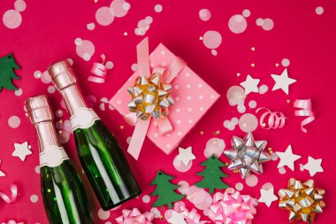 Şampanya şişeleri ve konfeti ve tinsel kırmızı arka plan ile hediye