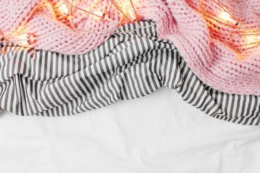 garland ile çizgili çarşaflar üzerinde pembe örgü şal