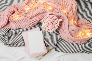 Bir kahve ve bir oral seks çok boş oyun kağıdı mockup yatakta sıcak ekose sarılı. Sonbahar ya da kış kavramı. Düz yatıyordu, en iyi görünümü