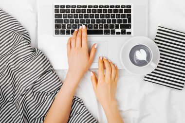 Genç kadın serbest meslek yatakta dizüstü bilgisayar ile çalışma, 