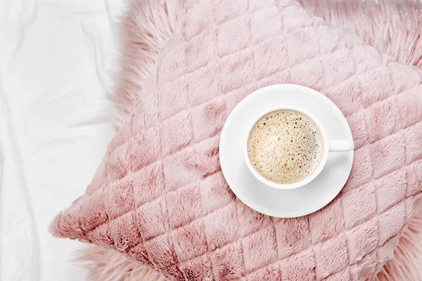 cup of coffee on pink fluffy pillow