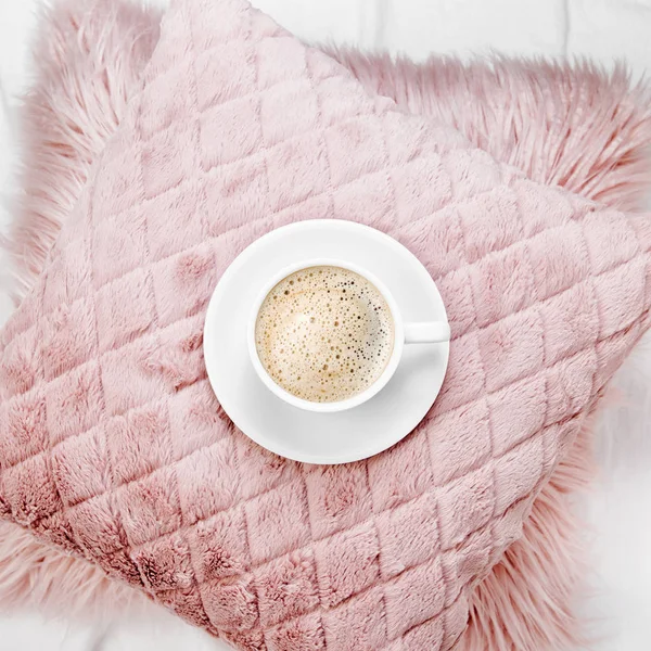 cup of coffee on pink fluffy pillow