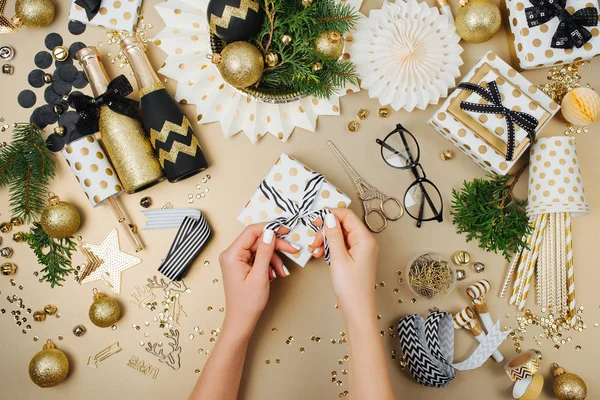 女性手附加弓到礼品盒包围的圣诞装饰品 — 图库照片