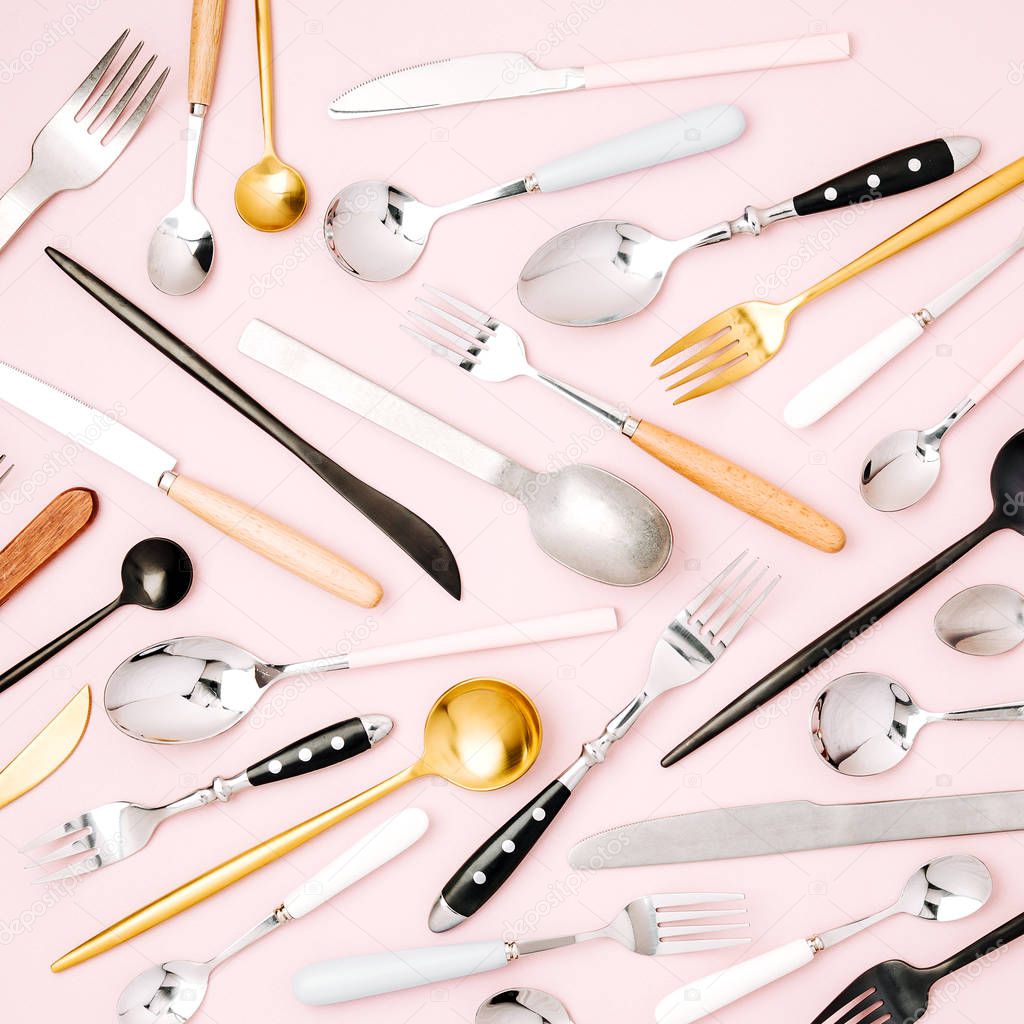 various knives, spoons and forks on pastel pink background