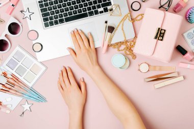 Moda blogger laptop ile çalışma. Kadın Aksesuar, kozmetik ürünleri soluk pembe tablo ile çalışma alanı. düz yatıyordu, en iyi görünümü