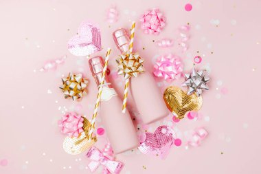 Mini şişe şampanya konfeti ve tinsel soluk pembe bir arka plan üzerinde. Sevgililer günü veya Doğum günü partisi konsepti tema. Düz yatıyordu, en iyi görünümü