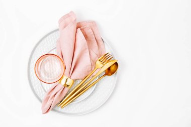 Kutlama masası. Beyaz arka planda pembe peçeteli tabak ve çatal bıçak takımı. Güzel düz yatak düzeni.