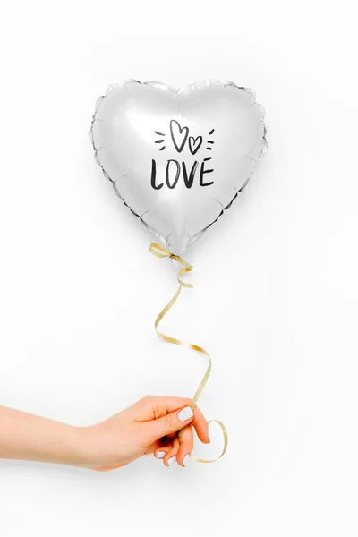 Female hands hold Balloon of heart shaped foil on white background. Love concept. Holiday celebration. Valentine\'s Day or wedding/bachelorette party decoration. Metallic balloon