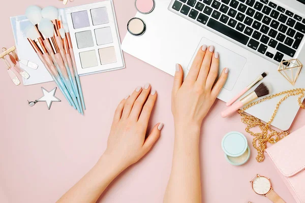 Moda blogger laptop ile çalışma. Kadın Aksesuar, kozmetik ürünleri soluk pembe tablo ile çalışma alanı. düz yatıyordu, en iyi görünümü