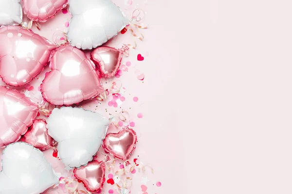 Hava balonları, kalp folyo pastel pembe bir arka plan üzerinde şeklinde. Aşk kavramı. Tatil kutlaması. Sevgililer günü veya düğün/bachelorette parti dekorasyon. Metalik balon