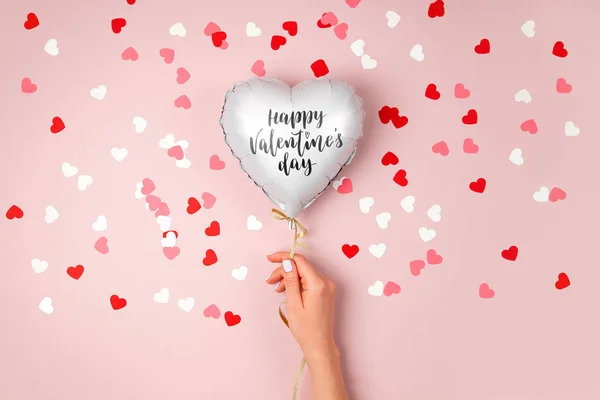 女性の手は ハート パステル ピンク背景に箔の風船を保持します 愛の概念 休日のお祝い バレンタインや結婚式 独身パーティーの装飾 メタリックバルーン — ストック写真