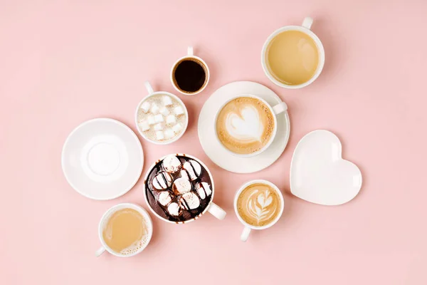 Various kinds of coffee in cups of different size on pale pink background.  Coffee  Time concept.  Flat lay, top view