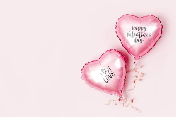 Air Balloons of heart shaped foil  on pastel pink background. Love concept. Holiday celebration. Valentine\'s Day or wedding/bachelorette party decoration. Metallic balloon