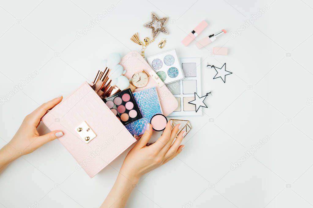 Female hands hold Makeup bag with cosmetic beauty products. Flat lay, top view. Beauty and Fashion concept