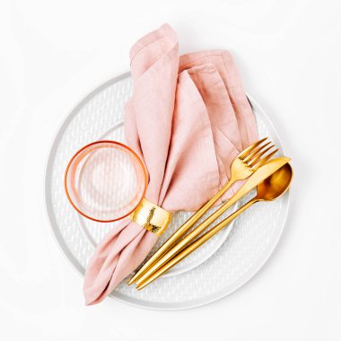 Kutlama masası. Beyaz arka planda pembe peçeteli tabak ve çatal bıçak takımı. Güzel düz yatak düzeni.