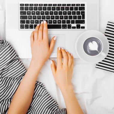 Genç kadın serbest meslek yatakta dizüstü bilgisayar ile çalışma, 