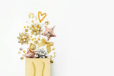 Parlak Noel süsleri ve hediyeleri ile alışveriş torbasında beyaz zemin üzerine altın yay. Noel alışveriş kavramı. Düz yatıyordu, en iyi görünümü