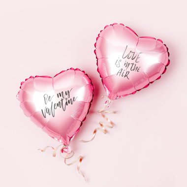 Hava balonları, kalp folyo pastel pembe bir arka plan üzerinde şeklinde. Aşk kavramı. Tatil kutlaması. Sevgililer günü veya düğün/bachelorette parti dekorasyon. Metalik balon