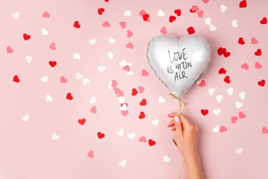 Eller pastel pembe arka plan folyoyu şeklinde kalp balon tutun. Aşk kavramı. Tatil kutlaması. Sevgililer günü veya düğün/bachelorette parti dekorasyon. Metalik balon