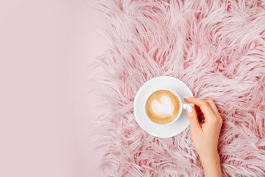 Bir fincan kahve kabarık kürk şal üzerinde tutan eller. Düz yatıyordu, en iyi görünümü