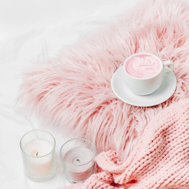 Bir fincan kahve mumlar ile pembe bir yastık üzerine ve yatağın üstüne bir battaniye. 
