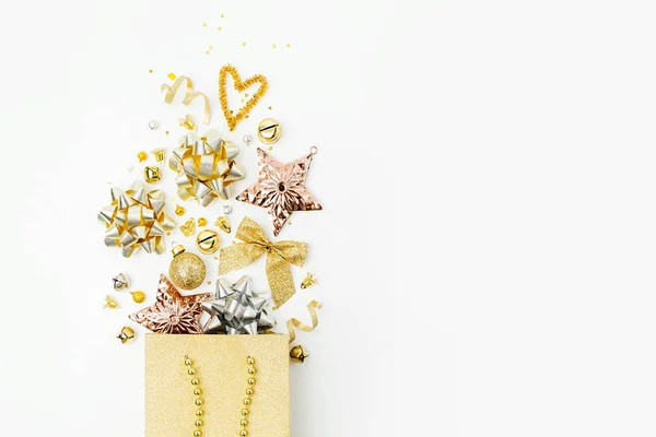 闪亮的圣诞装饰品和礼物与黄金弓在一个购物袋在白色的背景 圣诞购物概念 平面布局 顶部视图 — 图库照片