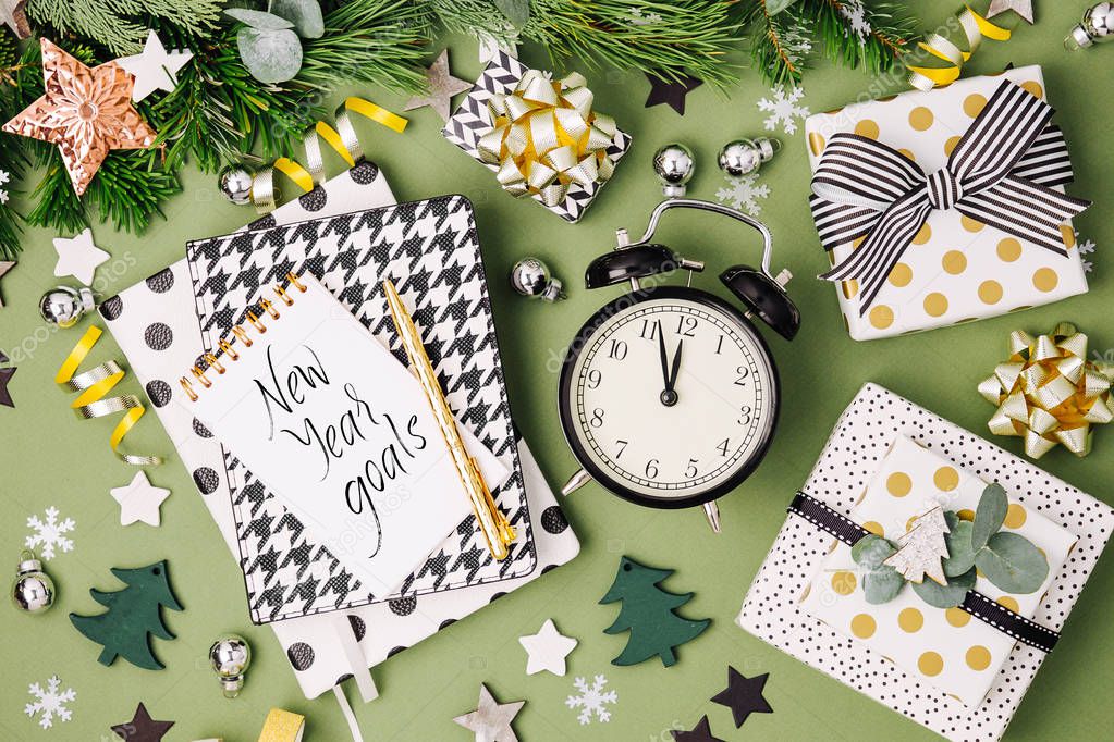 Christmas winter decorations, note books with alarm clock and gifts  on green background.  Flat lay, top view