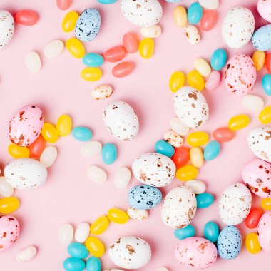 Şeker çikolata yumurta ve pembe bir arka plan üzerinde Jellybean