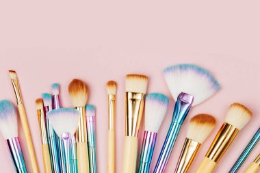 Pastel pembe arka plan çeşitli makyaj fırçaları moda