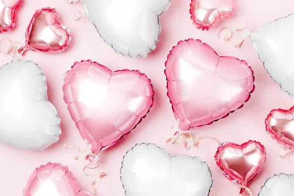 Air balloons of heart shaped foil on pastel pink background, Valentines day concept