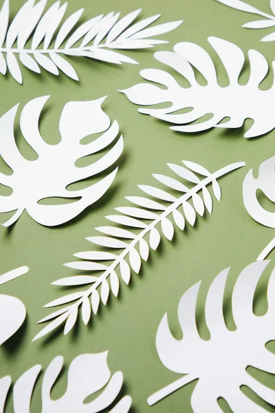 Various paper leaves on green background