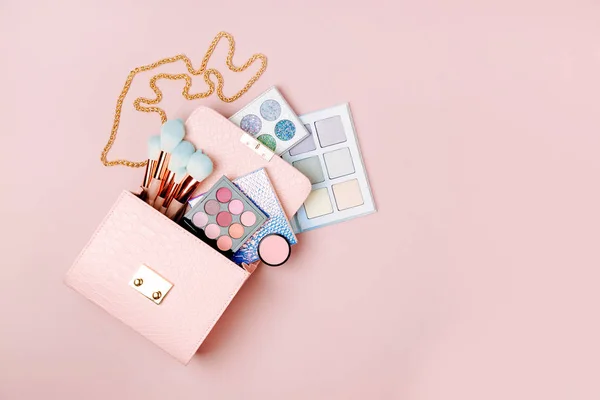 化妆品从化妆袋流动在柔和的粉红色的背景 — 图库照片