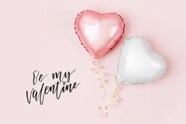 Air balloons of heart shaped foil on pastel pink background, Valentines day concept